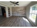Inviting living room featuring wood floors, a stone accent wall, and natural light at 21135 Sw Honeysuckle St, Dunnellon, FL 34431