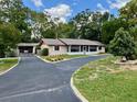 Inviting single-story home featuring a screened-in porch, American flag, and a circular driveway at 4145 Se 3Rd St, Ocala, FL 34471