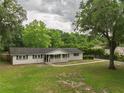 View of a single-story home with black shutters, a covered porch, and a large grassy yard at 4430 Se 47Th Pl, Ocala, FL 34480
