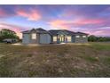 Charming single-story home featuring a stucco exterior, stone accents with a colorful dusk sky at 5489 Nantahala Ln, Lady Lake, FL 32159