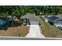 Aerial view of a well-maintained single-story home with a lush green lawn, two car garage, and spacious driveway at 6791 Se 100Th Pl, Belleview, FL 34420