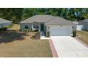 Inviting single-story home featuring a spacious driveway, attached two-car garage, and manicured front yard at 6791 Se 100Th Pl, Belleview, FL 34420