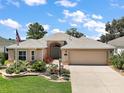 Well-maintained single-story home with lush green lawn, vibrant flowerbeds, and a spacious driveway at 8545 Se 168Th Kittredge Loop, The Villages, FL 32162