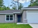 Close up of home featuring a front door, window with blinds, and attached garage at 9983 Sw 188Th Cir, Dunnellon, FL 34432
