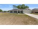 Well-maintained one-story home with a two car garage and a spacious front lawn on a sunny day at 10081 Se 68Th Ct, Belleview, FL 34420
