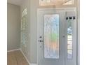 Home entryway featuring a glass door and sidelight next to a window with shutters and tile flooring at 11945 Se 171St Loop, Summerfield, FL 34491