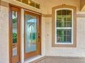 Close up view of a home entry with a decorative glass door and sidelight next to a window at 11945 Se 171St Loop, Summerfield, FL 34491