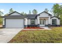 Exterior of a single-story home with a two-car garage, stylish accents, and landscaped yard at 12689 Sw 81St St, Dunnellon, FL 34432