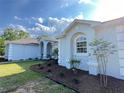 Close-up of the side entry showcasing white stucco, arched windows, and beautiful landscaping at 13430 Ne 30Th Ct, Anthony, FL 32617