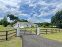 Attractive home with a metal gate at the driveway entrance, a side-entry garage, and a lush green lawn at 13430 Ne 30Th Ct, Anthony, FL 32617