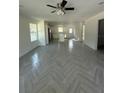 Open-concept living area featuring stylish herringbone floors, ample natural light, and modern ceiling fan at 14173 Se 41St Ter, Summerfield, FL 34491