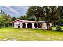 Home with a pink and red roof and white exterior, accented by arched entryways and mature trees at 16850 Se 19Th Ct, Summerfield, FL 34491