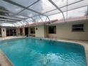 Enclosed pool with concrete deck and home exterior with a red roof in the background at 16850 Se 19Th Ct, Summerfield, FL 34491