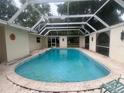 Enclosed pool with concrete deck and home exterior featuring glass windows and doors at 16850 Se 19Th Ct, Summerfield, FL 34491