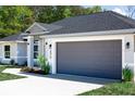 Attached two-car garage with sleek gray door and exterior lighting at 174 Sequioa Trl, Ocklawaha, FL 32179