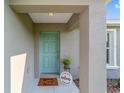 Inviting front entry with a vibrant turquoise door, a 'Welcome' mat, and decorative potted plants at 204 Emerald Loop Way, Ocala, FL 34472