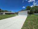 Exterior showcasing the driveway, two-car garage, and landscaped front yard at 235 Locust Pass Ln, Ocala, FL 34472