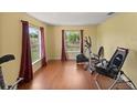 Spacious exercise room with hardwood floors, curtains, and a variety of workout equipment at 3792 Sw 152Nd Ct, Ocala, FL 34481