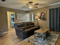 Comfortable living room with a leather couch, wood floors, ceiling fan, and neutral color scheme at 4513 Nw 30Th Pl, Ocala, FL 34482