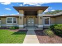 Inviting front entrance with large pillars, a decorative door, and beautifully landscaped surroundings at 5420 Sw 86Th Ln, Ocala, FL 34476
