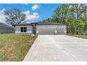 A modern single-story home featuring an attached two-car garage, stylish exterior, and well-kept lawn at 9405 Se 159Th Ln, Summerfield, FL 34491