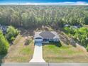 An aerial view highlighting the home's setting, spacious lot, and proximity to lush woods at 9525 Sw 200 Ct, Dunnellon, FL 34431
