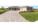 Attractive home featuring a brick driveway, green lawn, and a two-car garage, creating a welcoming atmosphere at 10530 Sw 98Th Pl, Ocala, FL 34481