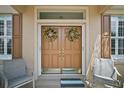Elegant double front doors with decorative wreaths, sidelights, and cozy chairs on the porch at 12165 Se 91St Ave, Summerfield, FL 34491