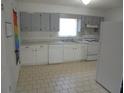 A clean kitchen featuring white appliances, cabinets, and tile flooring with a large window above the sink at 2912 Ne 24Th Ct, Ocala, FL 34479
