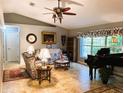 Inviting living room featuring tile flooring, a decorative ceiling fan, and a large window with a view of the yard at 3579 Sw Shorewood Dr, Dunnellon, FL 34431