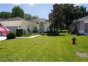 Well-manicured lawn, lush landscaping, and a vibrant American flag add charm to this home's exterior at 6836 Sw 112Th St, Ocala, FL 34476