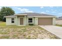 Charming single-story home with a two-car garage, grassy front yard, and a welcoming entrance at 69 Juniper Trail Loop, Ocala, FL 34480