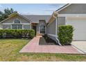 Home with a cozy entrance, manicured bushes, and a red brick walkway, enhancing its curb appeal at 1317 Ravida Woods Dr, Apopka, FL 32703