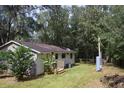A view of the home's back exterior and the grassy backyard surrounded by mature trees offering nice shade at 14121 Nw Highway 225, Reddick, FL 32686