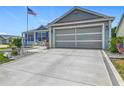 Charming home featuring blue shutters, a two-car garage, and a well-manicured yard with an American flag at 16954 Se 93Rd Cuthbert Cir, The Villages, FL 32162