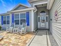 Inviting front porch with rocking chairs and beautiful brickwork leading to the home's entrance at 16954 Se 93Rd Cuthbert Cir, The Villages, FL 32162