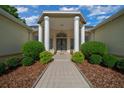 Home's entrance showing walkway leading to the front door framed by elegant columns and manicured bushes at 2272 Se Laurel Run Dr, Ocala, FL 34471