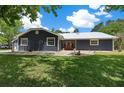 Charming single-story home featuring navy siding, metal roof, well-manicured lawn, and welcoming front entrance with vibrant orange door at 260 Country Circle W Dr, Port Orange, FL 32128