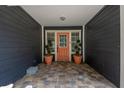 Inviting front porch featuring a vibrant orange door framed by elegant topiaries and a decorative, tiled walkway at 260 Country Circle W Dr, Port Orange, FL 32128