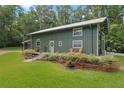 Unique green home featuring a metal roof, inviting porch with seating, and well-maintained landscaping at 400 Se 90Th St, Ocala, FL 34480