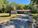 Attractive home showcasing a paved driveway, mature palm and a lush green lawn at 439 Sw Shorewood Dr, Dunnellon, FL 34431
