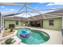 A covered pool area with nice blue water and an inflatable raft, and a patio area with chairs and a table at 4966 Sw 107Th Loop, Ocala, FL 34476