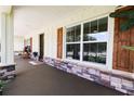 Spacious front porch features a stained concrete floor, stone pillars, and stylish window shutters at 6600 Sw 109Th Ln, Ocala, FL 34476