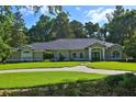 Single-story residence featuring a well-groomed lawn, a circular driveway, and lush surrounding trees at 7939 Se 12Th Cir, Ocala, FL 34480