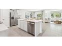 Bright kitchen island with stainless steel dishwasher overlooking the living area with stylish decor and lots of light at 10490 Se 162Nd Place Rd, Summerfield, FL 34491