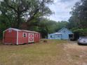 Exterior of home with red outbuilding on a large lot surrounded by mature trees at 10805 Se 102Nd Pl, Ocala, FL 34472