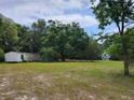 View of property with trees surrounding the home and an additional building on a grassy lot at 10805 Se 102Nd Pl, Ocala, FL 34472