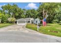 Charming single-story home featuring a well-manicured lawn, American flag and a welcoming two-car garage with paved driveway at 11569 Sw 75Th Cir, Ocala, FL 34476