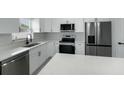 Modern kitchen featuring stainless steel appliances, quartz countertops, and white cabinets with black hardware at 12180 Se 89Th Ter, Belleview, FL 34420