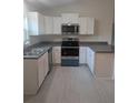 Modern kitchen featuring white cabinets, stainless steel appliances, and gray countertops at 15 Juniper Trail Crse, Ocala, FL 34480